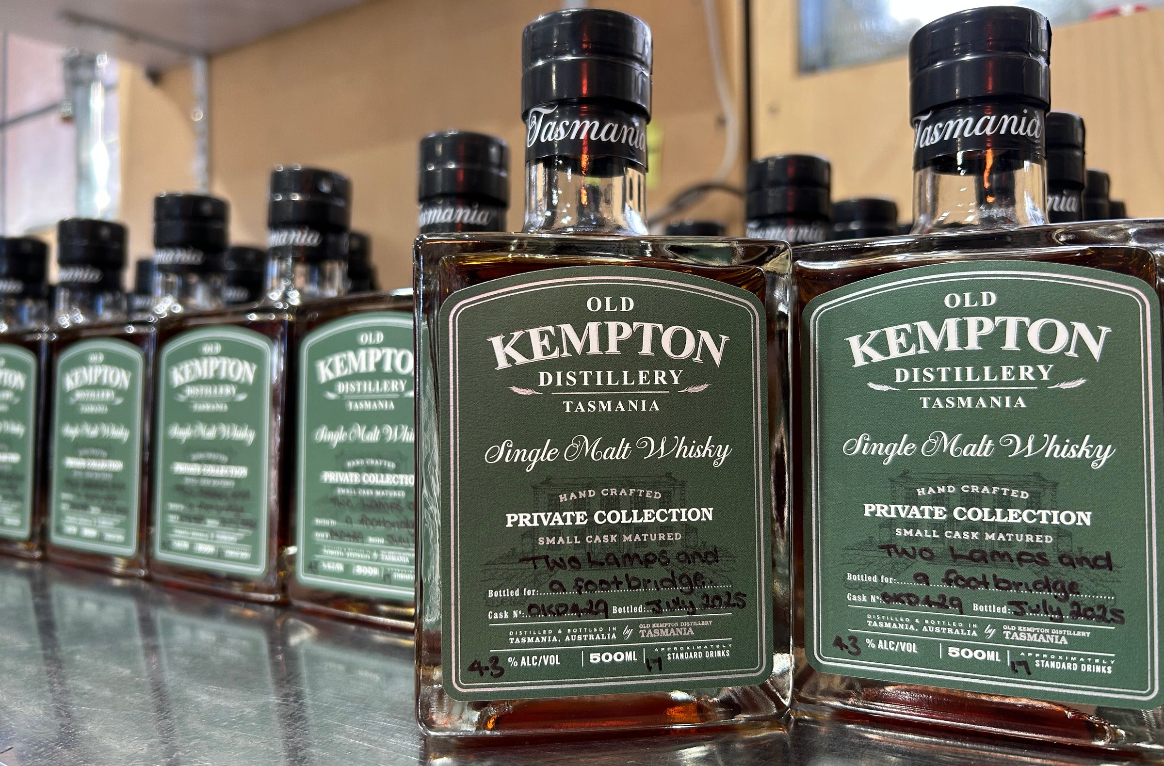 Bottles of Old Kempton Distillery Single Malt Whisky on a reflective surface.